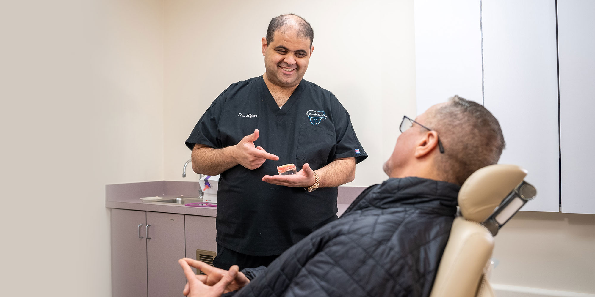 Mina Elfar, DMD showing a patient a model of dental implants