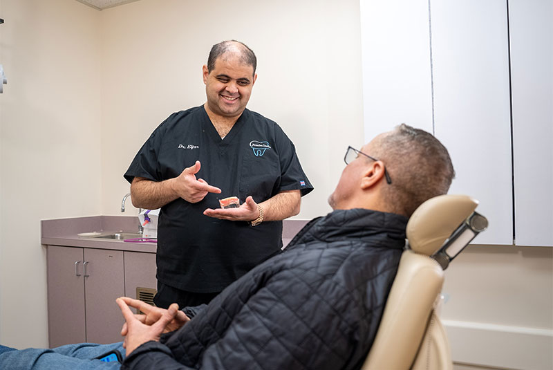 Mina Elfar, DMD showing patient a model of dental implants
